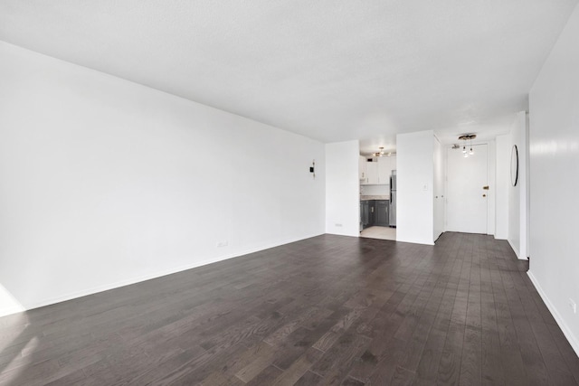 unfurnished living room featuring dark wood-style floors and baseboards