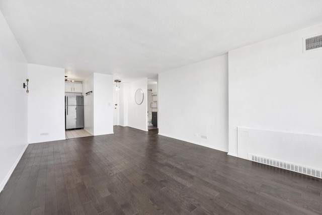 unfurnished living room with visible vents, baseboards, and wood finished floors