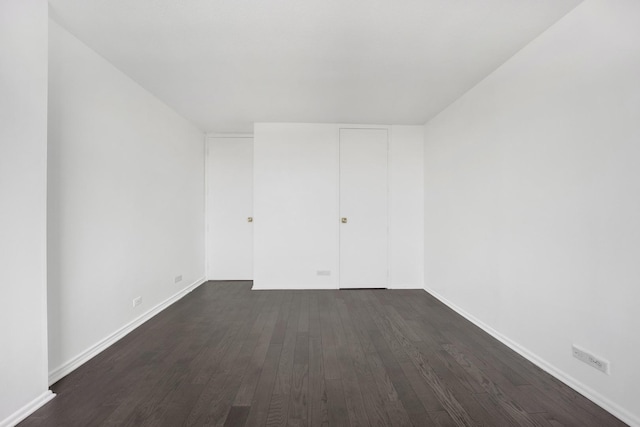 empty room featuring dark wood-style floors and baseboards