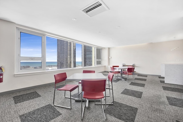 carpeted dining room with visible vents, a water view, and baseboards