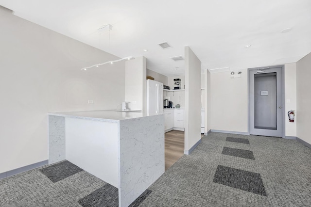 kitchen with baseboards, white cabinets, freestanding refrigerator, a peninsula, and light countertops