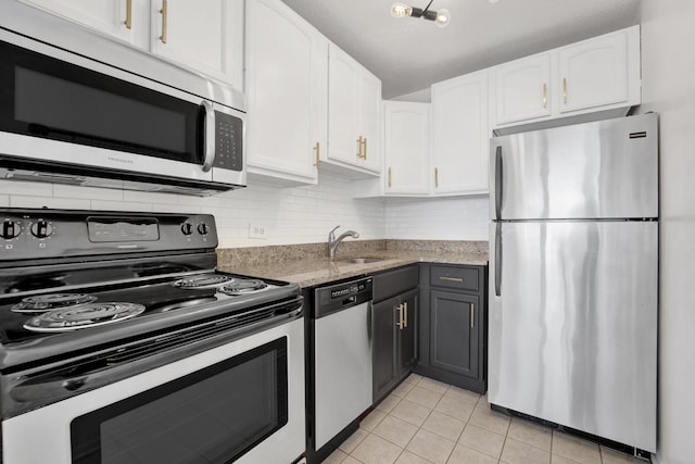 kitchen featuring light tile patterned floors, light stone counters, stainless steel appliances, white cabinetry, and backsplash