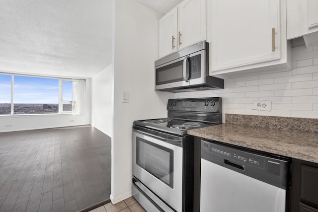 kitchen featuring decorative backsplash, appliances with stainless steel finishes, light wood-style floors, white cabinets, and a textured ceiling