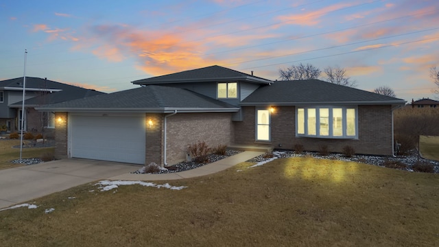 view of front facade with a garage, concrete driveway, brick siding, and a front yard