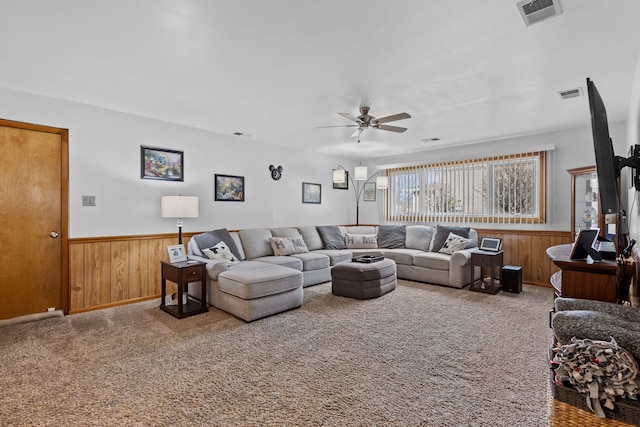 living area with a wainscoted wall, visible vents, and light colored carpet