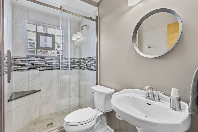 bathroom featuring a stall shower, a sink, and toilet