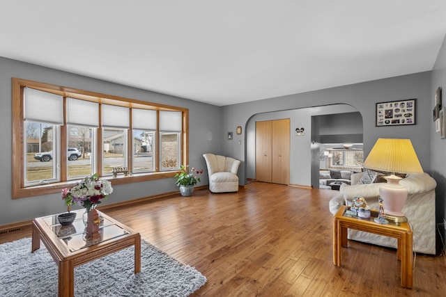 living area with wood-type flooring, visible vents, arched walkways, and baseboards