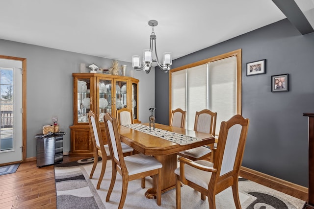 dining room featuring a chandelier, baseboards, and light wood-style floors