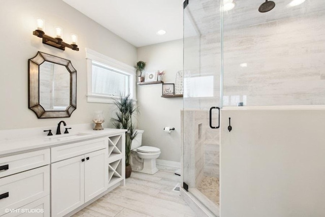 bathroom featuring toilet, a shower stall, baseboards, and vanity