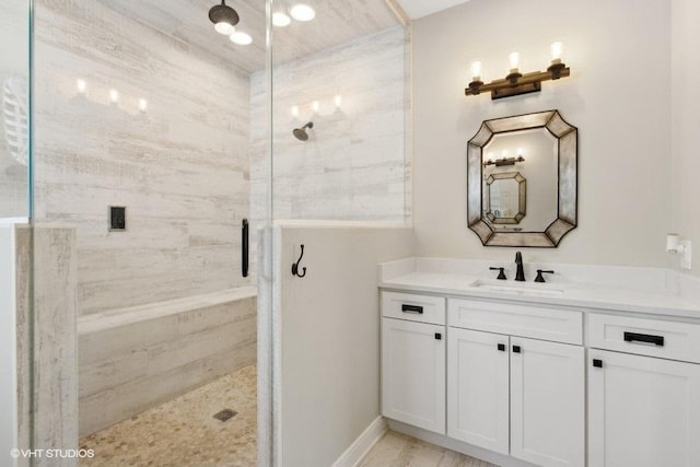 full bath featuring a stall shower, vanity, and baseboards