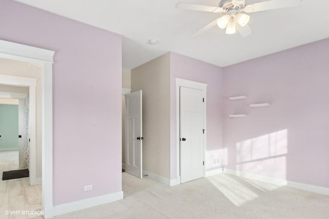 unfurnished bedroom featuring light carpet, a ceiling fan, and baseboards