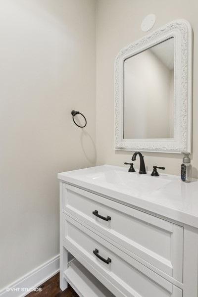 bathroom with baseboards, wood finished floors, and vanity