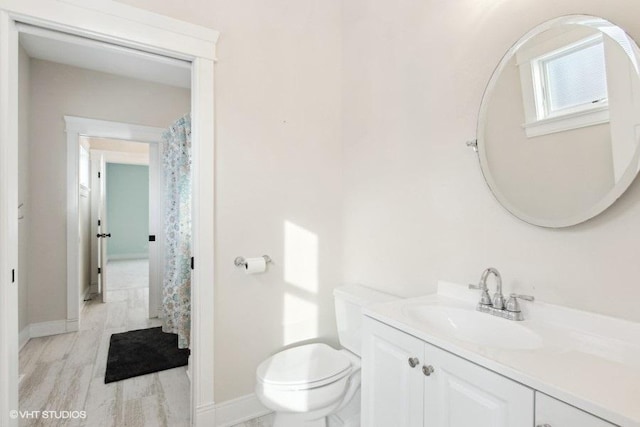 bathroom with baseboards, vanity, toilet, and wood finished floors