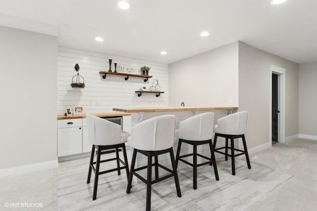 bar with recessed lighting, indoor wet bar, light carpet, and baseboards