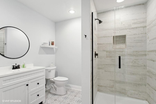 bathroom with toilet, a shower stall, baseboards, and vanity