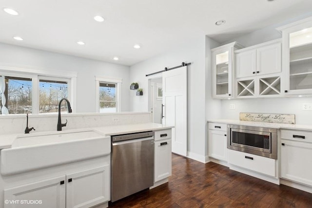 kitchen featuring stainless steel appliances, a barn door, light countertops, and glass insert cabinets