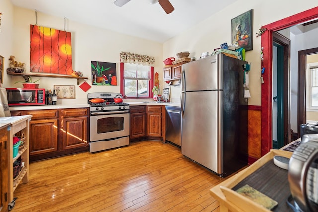 kitchen with stainless steel appliances, brown cabinetry, light wood-type flooring, and light countertops