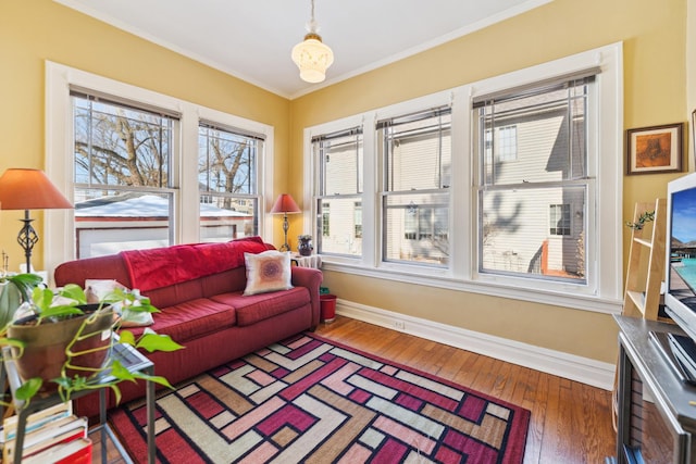 living area with ornamental molding, wood-type flooring, and baseboards