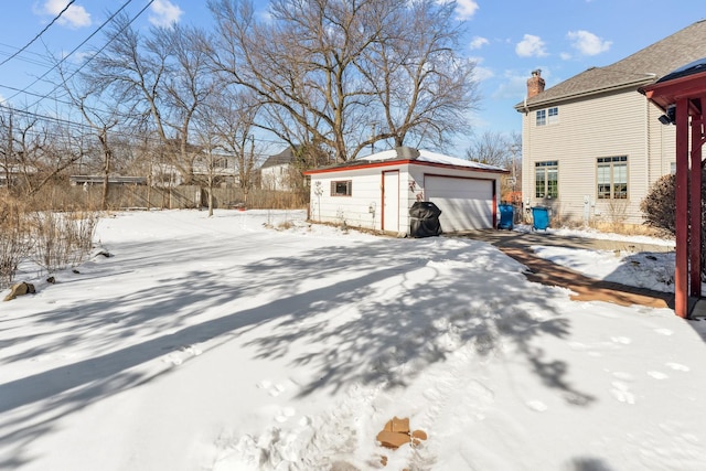 view of snowy exterior with an outbuilding and a garage