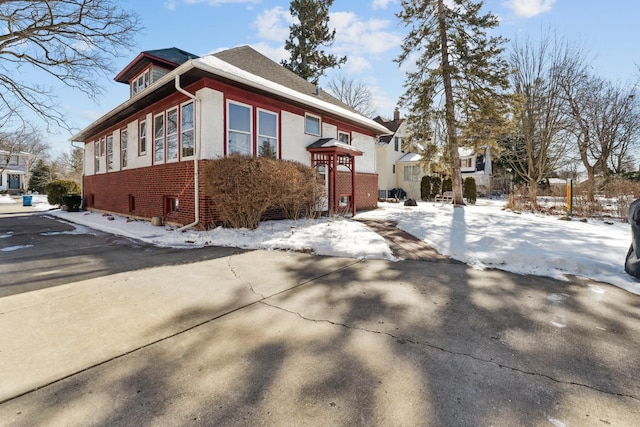 snow covered property with brick siding