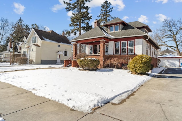 bungalow-style house featuring a shingled roof, brick siding, a detached garage, and a chimney