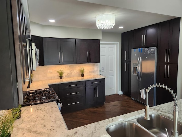 kitchen featuring tasteful backsplash, range with gas cooktop, a sink, and stainless steel refrigerator with ice dispenser