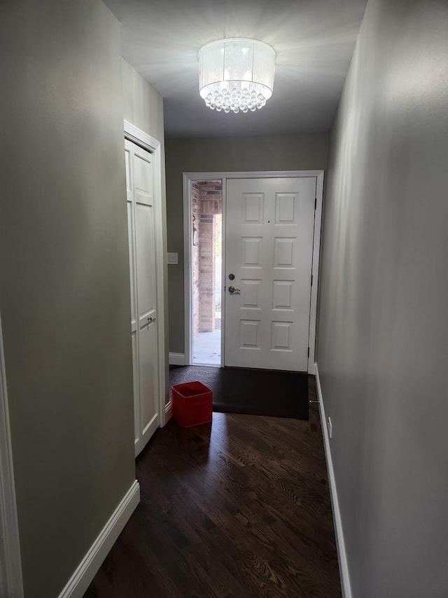 entrance foyer featuring a notable chandelier, dark wood-style flooring, and baseboards