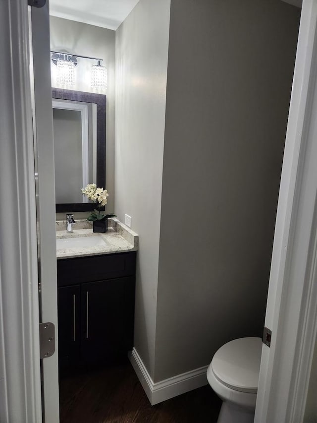 bathroom with toilet, baseboards, wood finished floors, and vanity