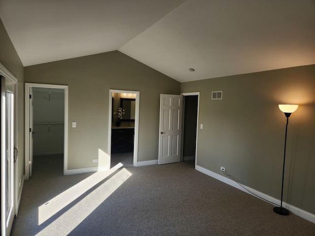 unfurnished bedroom featuring baseboards, visible vents, lofted ceiling, carpet, and a spacious closet