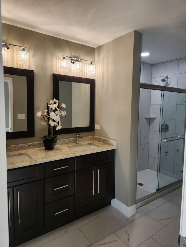 full bathroom featuring double vanity, baseboards, marble finish floor, a shower stall, and a sink