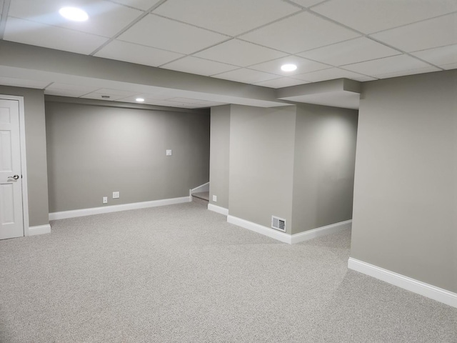 finished basement featuring carpet floors, baseboards, visible vents, and a drop ceiling