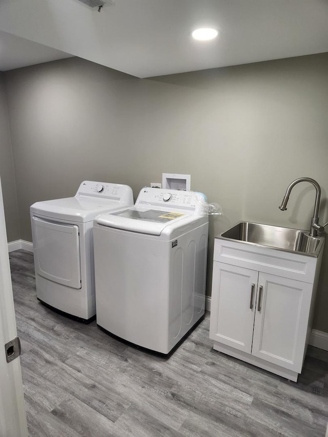 washroom with laundry area, separate washer and dryer, light wood-type flooring, and a sink