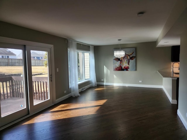 interior space with an inviting chandelier, a sink, baseboards, and wood finished floors