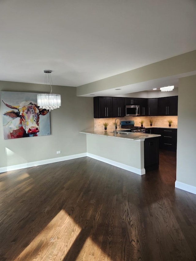 kitchen with tasteful backsplash, appliances with stainless steel finishes, dark cabinets, light countertops, and a sink