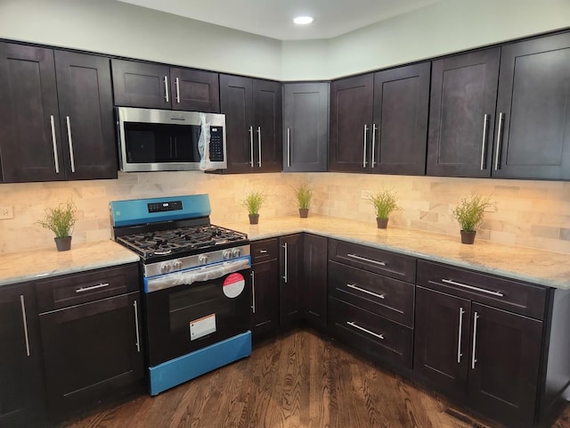 kitchen featuring decorative backsplash, light stone counters, stainless steel appliances, and dark wood-type flooring