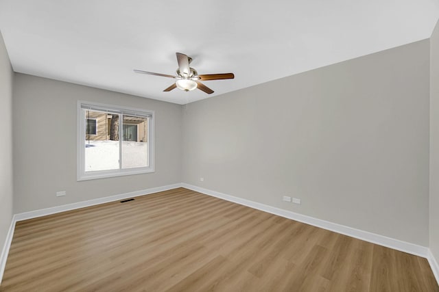 spare room with light wood finished floors, ceiling fan, and baseboards