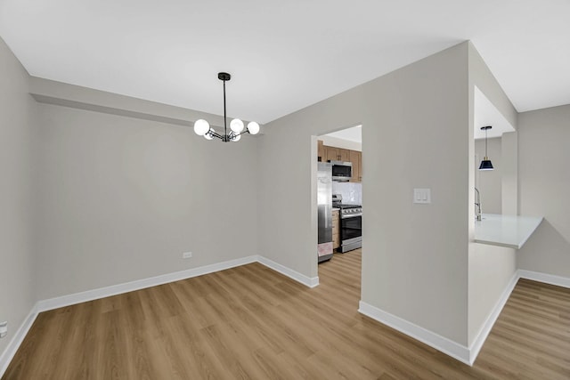 unfurnished dining area with an inviting chandelier, wood finished floors, and baseboards