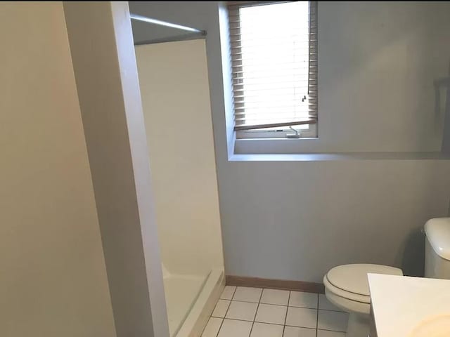 full bath with toilet, a stall shower, baseboards, and tile patterned floors