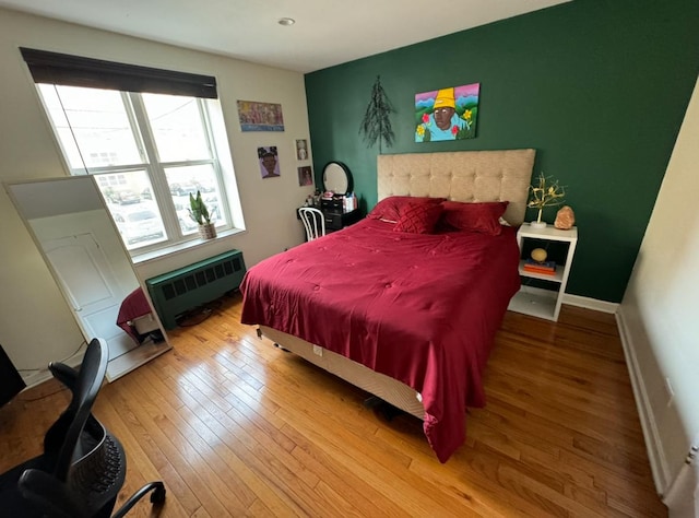 bedroom featuring baseboards, radiator heating unit, and wood finished floors