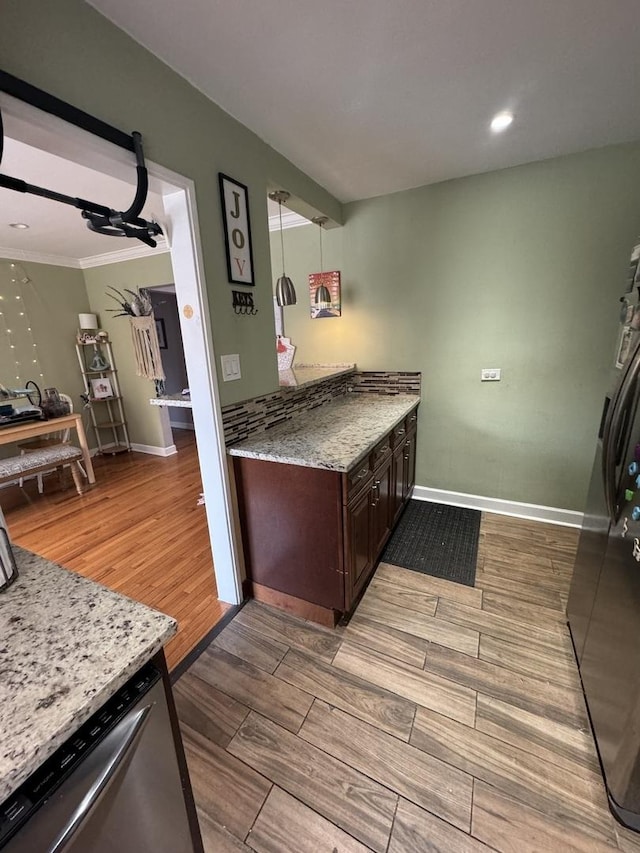 kitchen featuring light stone counters, wood finish floors, decorative light fixtures, stainless steel dishwasher, and dark brown cabinetry