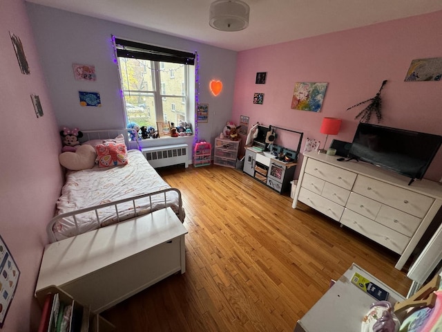 bedroom with light wood finished floors and radiator heating unit