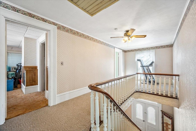 hall with wallpapered walls, baseboards, an upstairs landing, crown molding, and carpet flooring