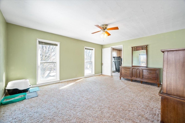 unfurnished bedroom featuring a ceiling fan, light colored carpet, and baseboards