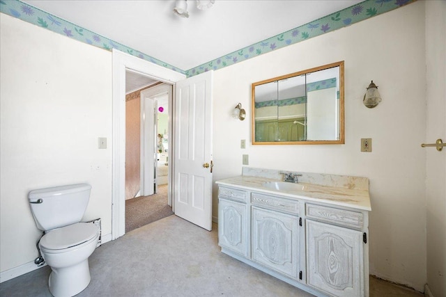 bathroom featuring toilet, vanity, and baseboards