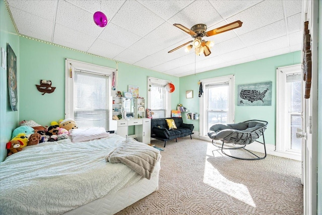 bedroom featuring light carpet, ceiling fan, and a paneled ceiling