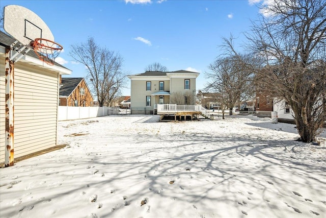 snow covered house featuring fence and a deck