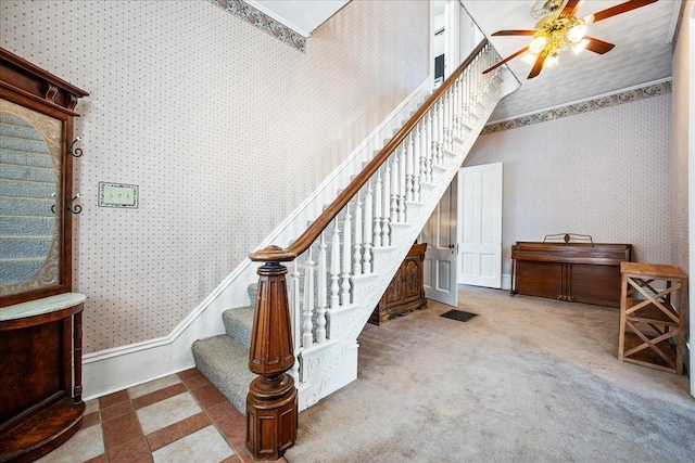 staircase with visible vents, ceiling fan, carpet flooring, and wallpapered walls