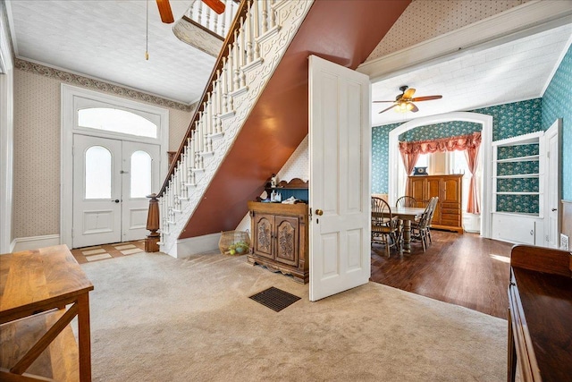 foyer with a wealth of natural light, carpet, stairway, and wallpapered walls