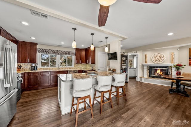 kitchen featuring visible vents, decorative backsplash, a glass covered fireplace, dark wood-style floors, and stainless steel appliances