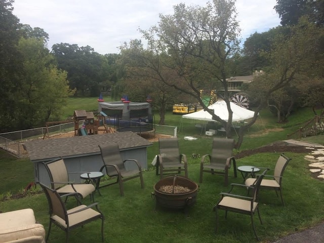 view of community featuring fence, a fire pit, and a lawn